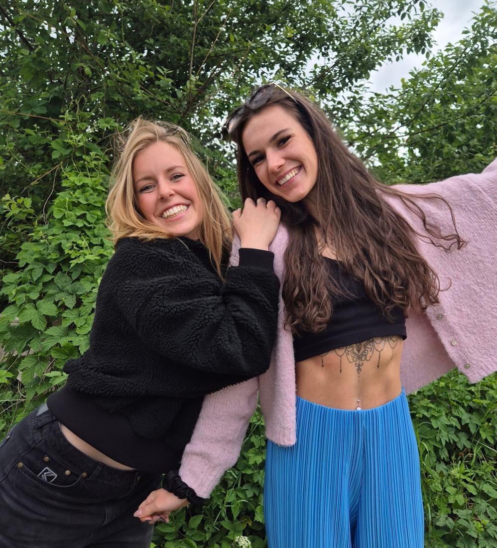 Kristina und Rebecca lachen vor grünen Büschen